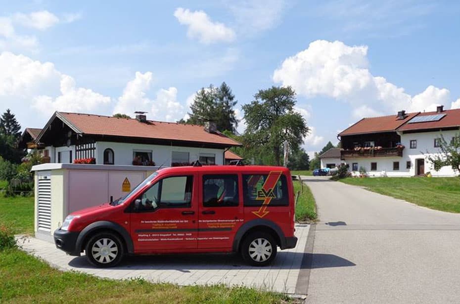 Roter EVA-Servicewagen vor einer Trafostation in einer Siedlung mit Bauernhäusern.