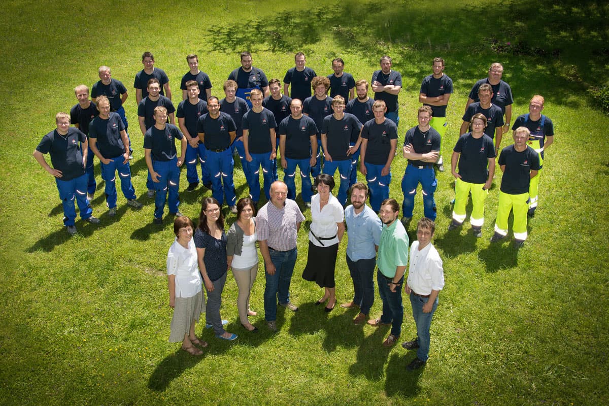 Gruppenfoto des EVA-Serviceteams auf einer Wiese: Monteure in dunkelblauer Arbeitskleidung, davor das Büroteam.