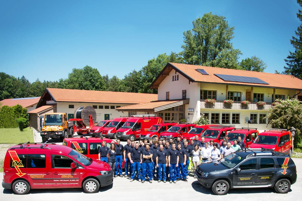 Das EVA-Team vor dem Firmengebäude in Höpfling, umgeben von roten Servicefahrzeugen.