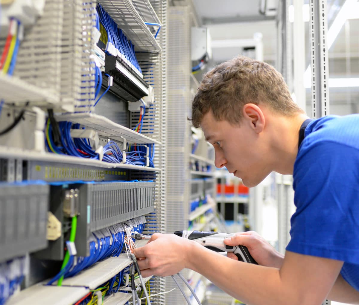 Ein Elektriker verdrahtet einen Schaltschrank mit dem Akkuschrauber.